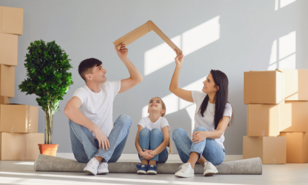 mladá rodina sedí v novém prázdném bytě vedle krabic s věcmi